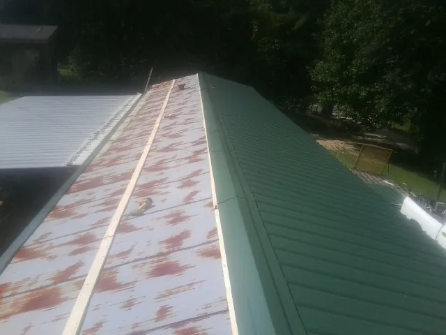 Old rusted panels beside newly installed green metal roofing — Wind Damage Roof Repair by Roofing Brothers in South Hutchinson
