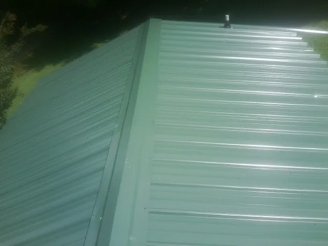 New green metal panels meeting at the ridge of a roof — Flat Roof Repair work by our crew in South Hutchinson