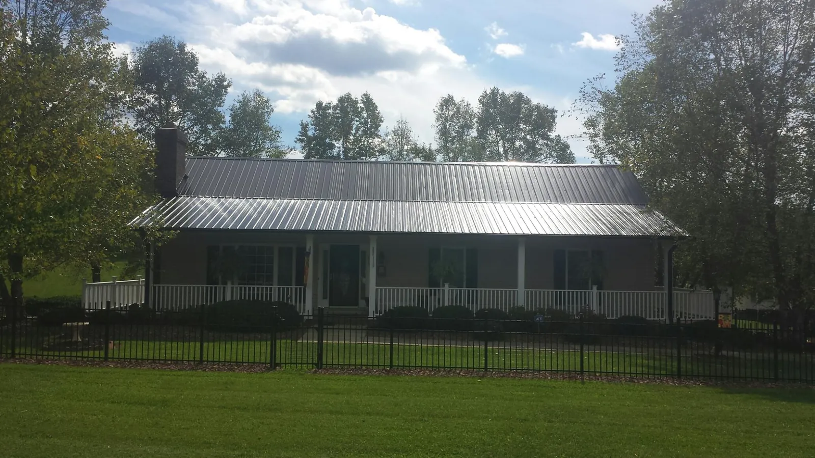 Gray metal roof on a brick ranch with a full width front porch — Gutter Guard Installation work by our crew in South Hutchinson