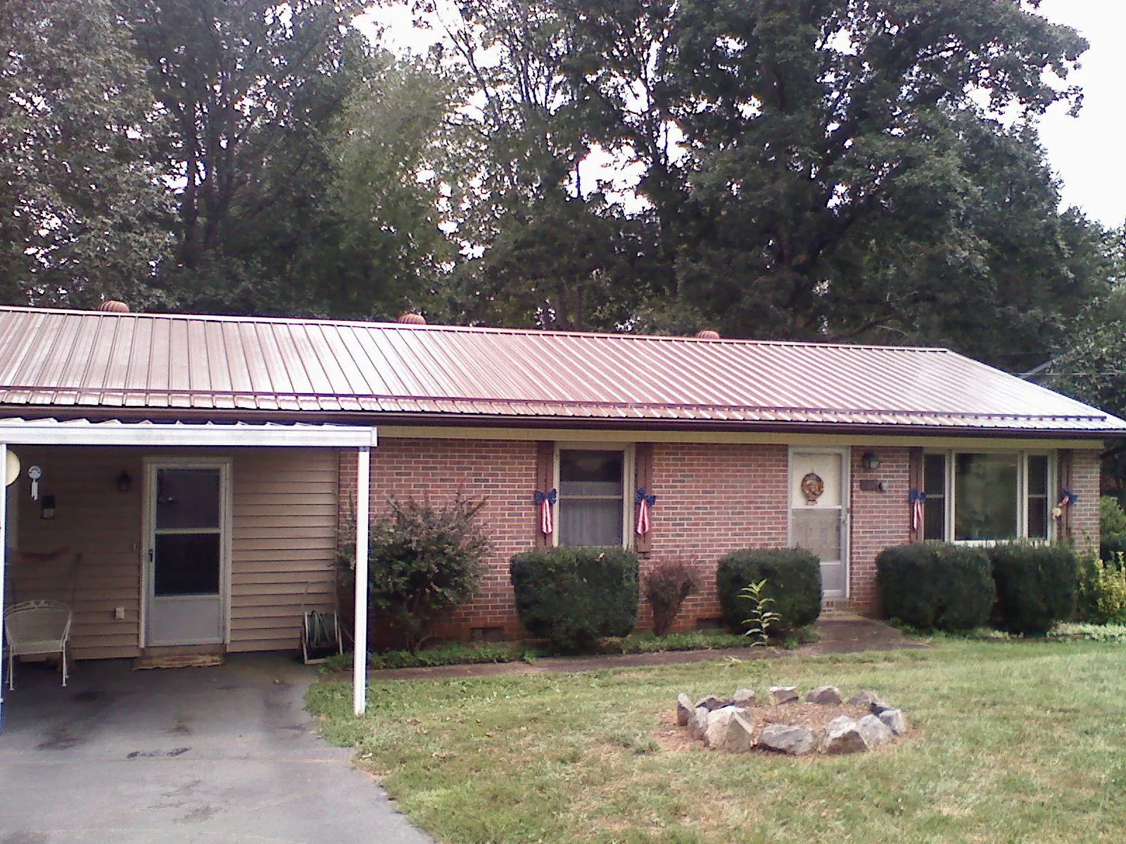 Bronze metal roof and carport on a brick ranch home — Roof Repair work by our crew in South Hutchinson