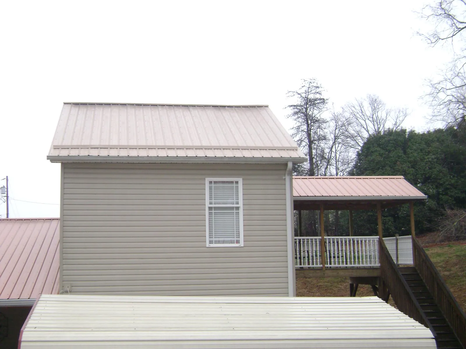 Tan metal roofs on a two story addition and attached porch, from a Roof Replacement job in South Hutchinson