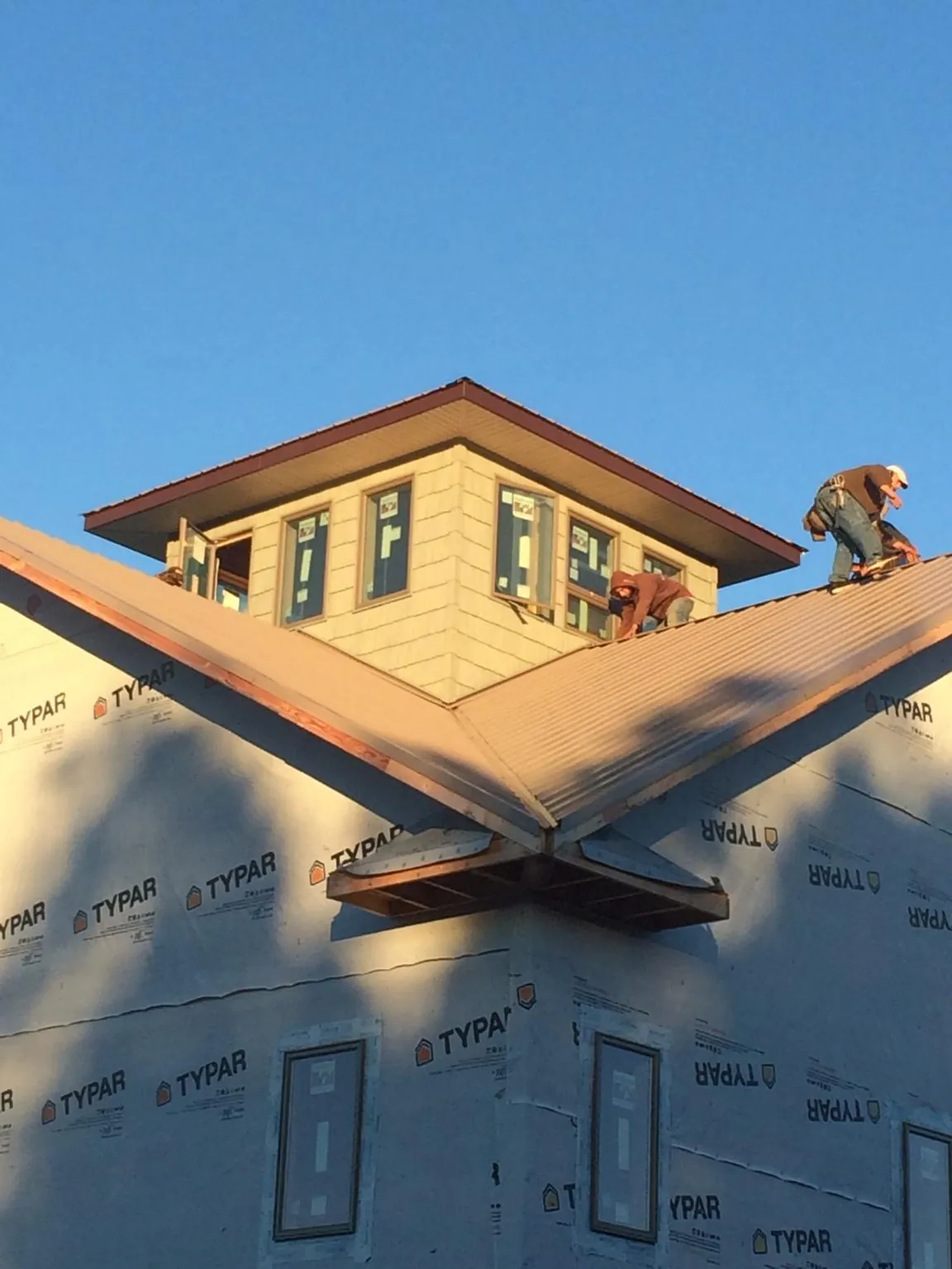Roofers working around a rooftop cupola on a new metal roof at sunset — Roof Waterproofing in South Hutchinson by Roofing Brothers